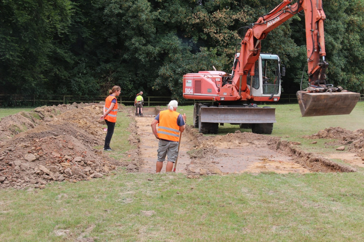 Baggerarbeiten am ersten Grabungstag; die Schnittbreite ergibt sich durch den parallelen Abtrag des Oberbodens auf Breite der Baggerschaufel.